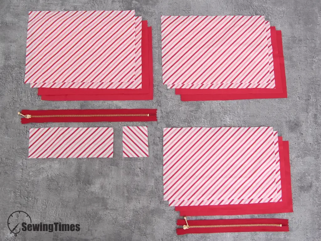 Pre-cut fabric pieces and zippers laid out for sewing a 5-pocket organizer pouch in red and white stripes