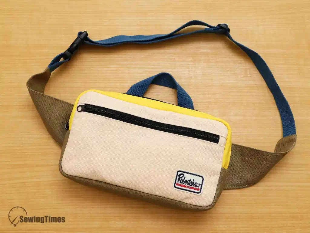 A completed handmade khaki canvas sling bag with a black buckle and a minimalist utility design, shown against a neutral background.