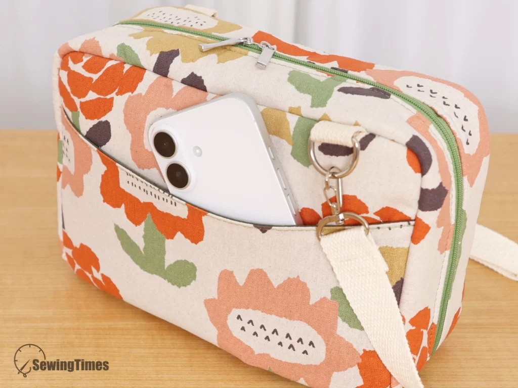 Close-up of the back exterior pocket of the floral accordion bag, showing a white smartphone easily sliding inside for quick access.