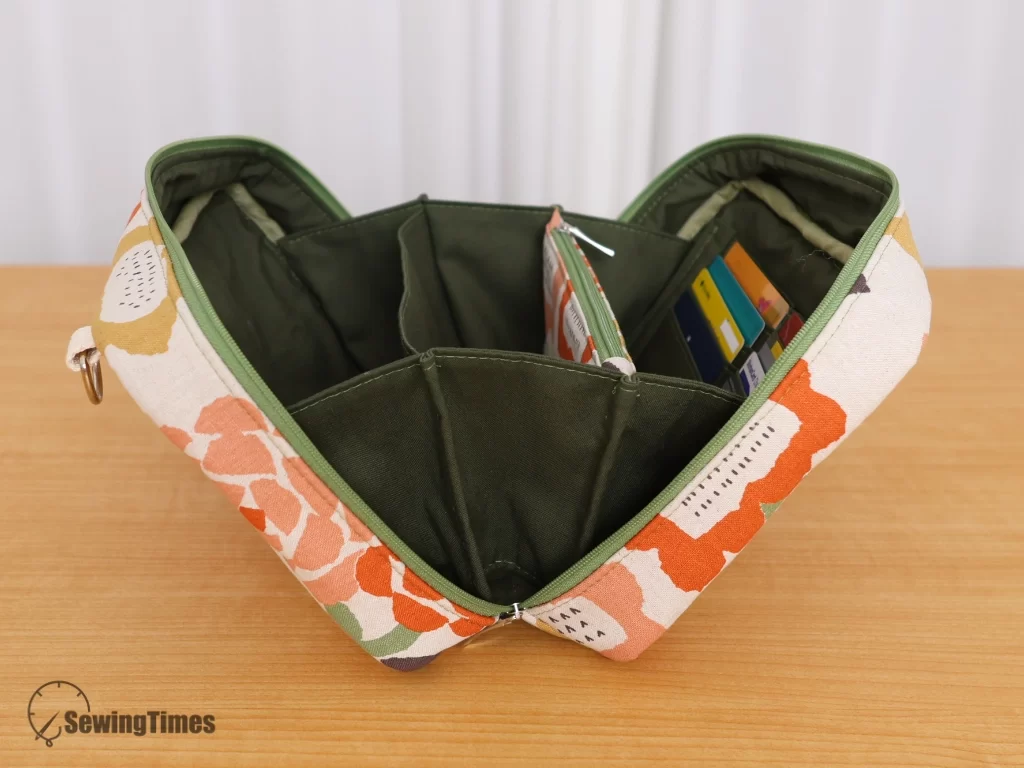Top-down view of the accordion bag opened wide, revealing an olive green multi-compartment lining and built-in card slots.