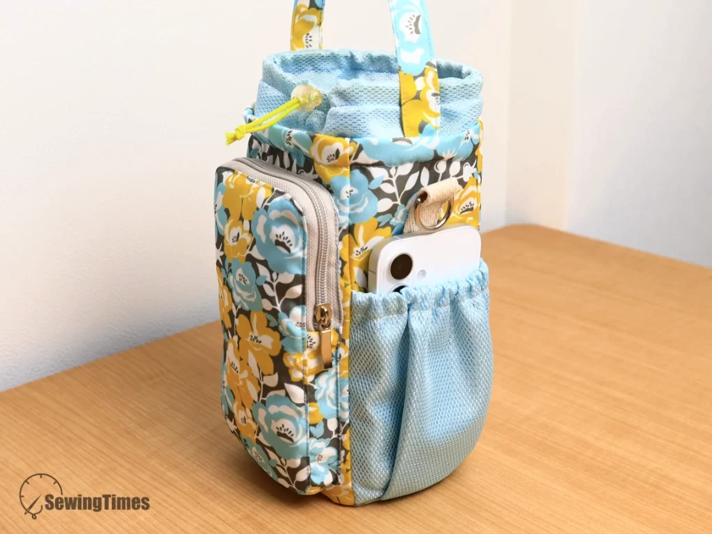 Side elastic mesh pocket of the floral water bottle bag storing a white smartphone.