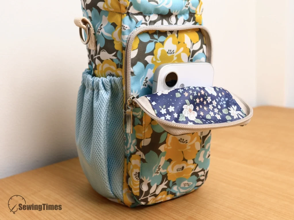 Unzipped front phone pocket of the water bottle pouch showing a white smartphone sticking out slightly and the floral lining inside.