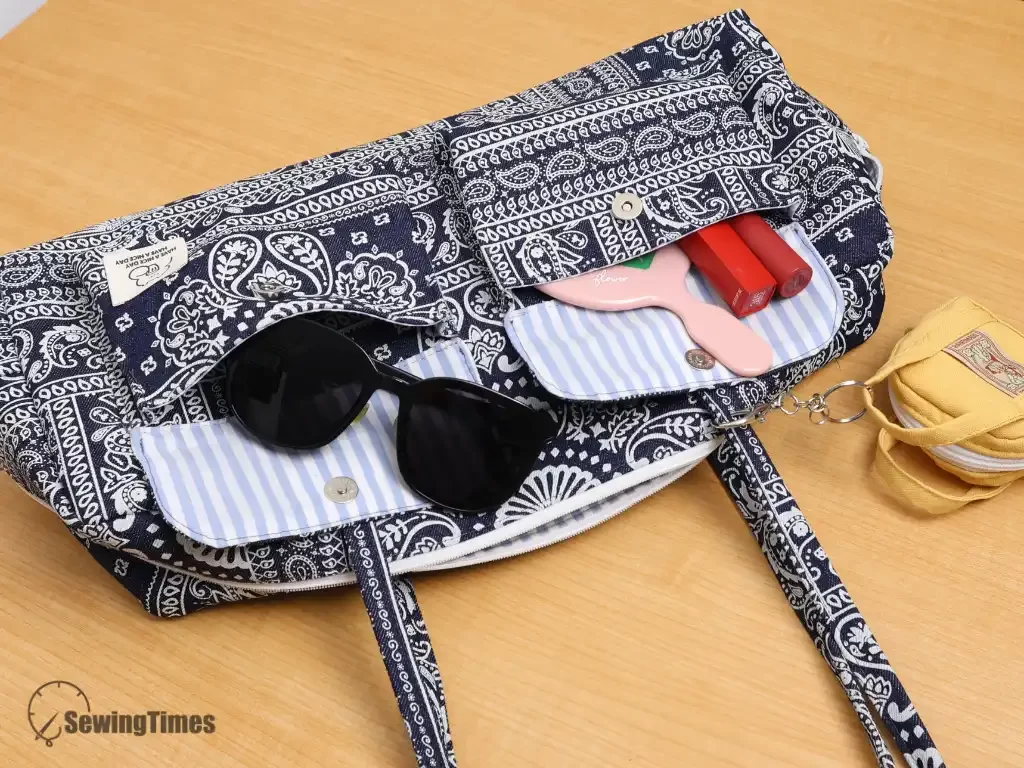 Close-up of a denim shoulder bag with open cargo pockets containing sunglasses and accessories, highlighting functional storage for daily essentials.