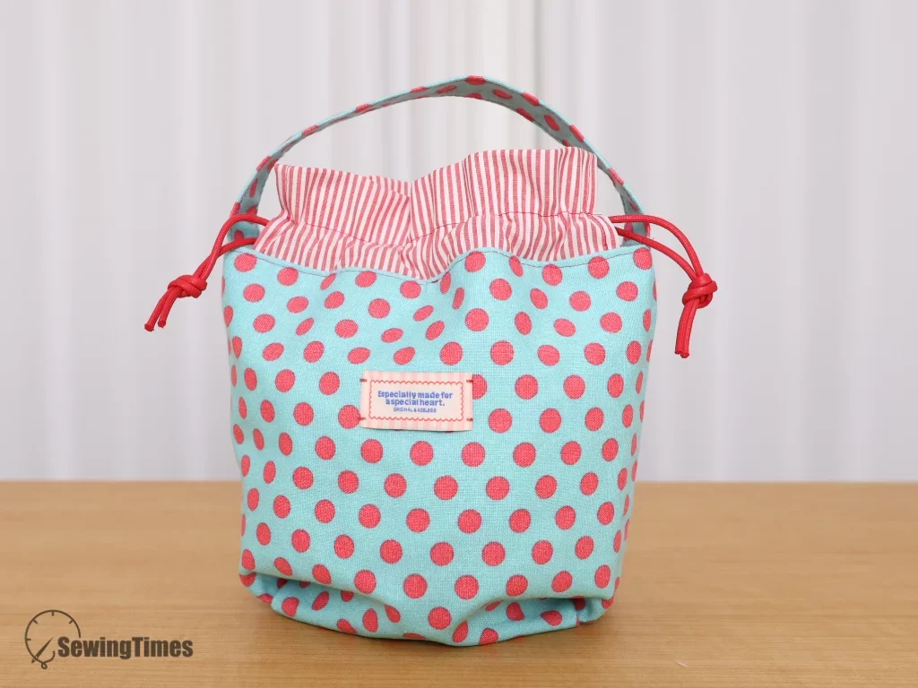 Completed polka dot one-handle drawstring bag standing on a wooden surface.