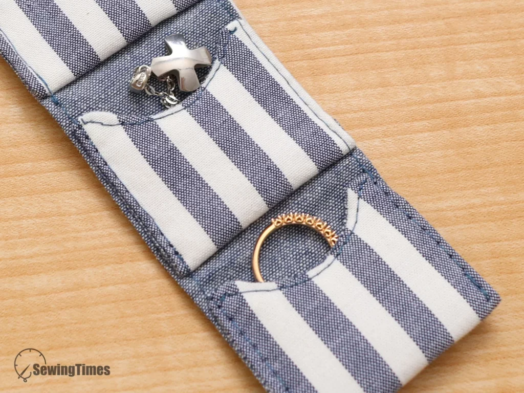 Close-up of a gold ring tucked into a striped fabric pocket, showing the professional stitching and finish of the DIY pouch.