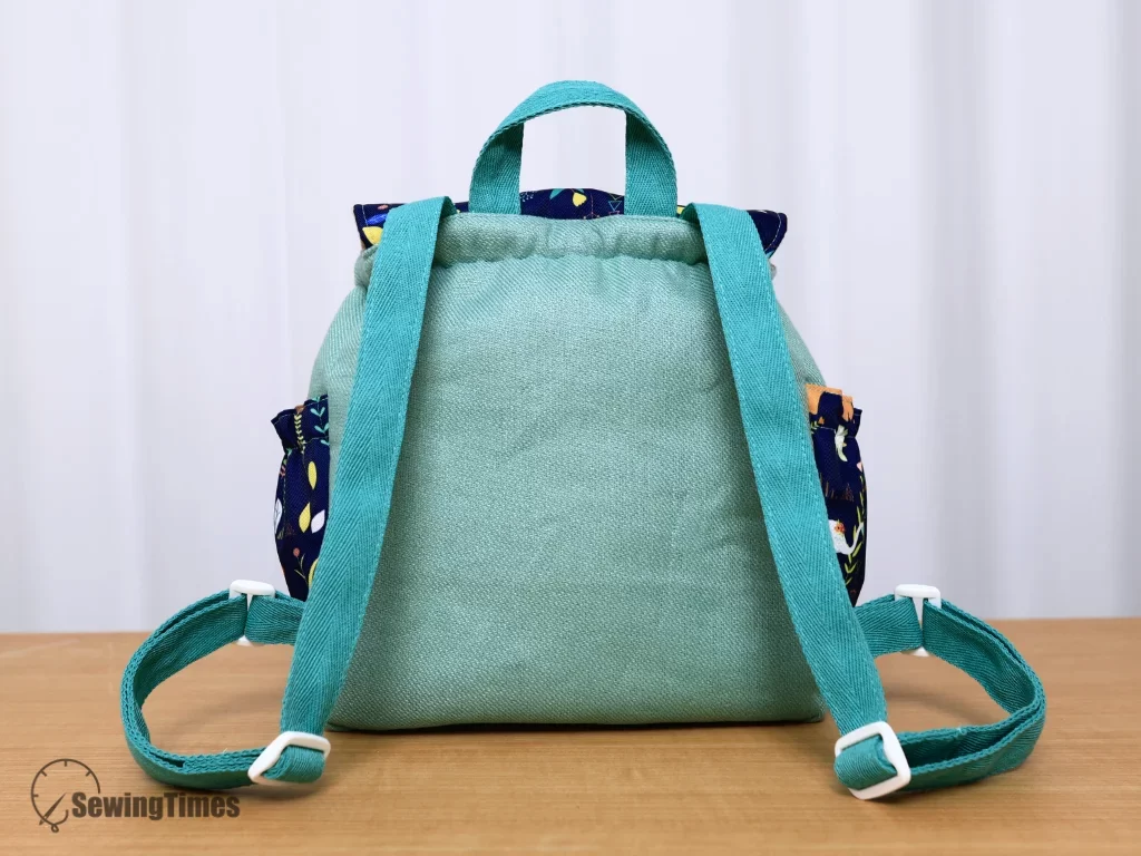Rear view of green fabric kids backpack featuring comfortable adjustable shoulder straps and top grab handle.