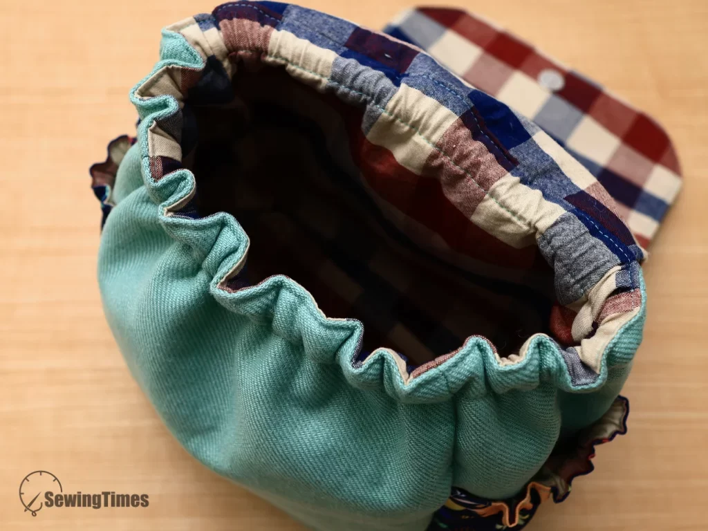 Top-down view into the main compartment of the sewn kids backpack showing plaid lining and wide gather top opening.