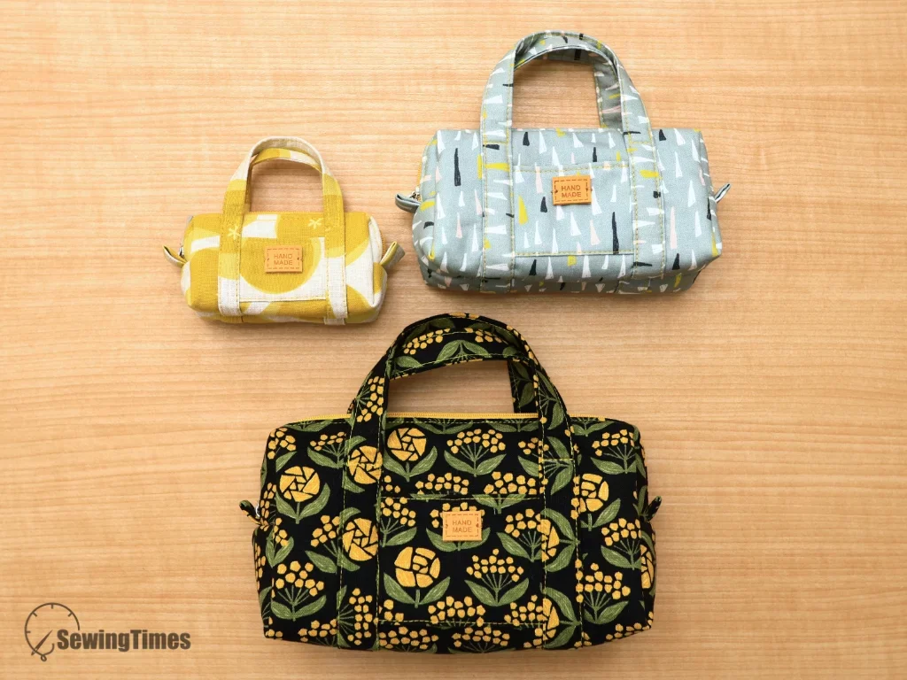 Flat lay of three finished handmade mini duffle pouches in yellow, grey, and floral black fabric.
