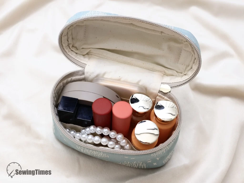 Fully opened light blue oval zipper pouch showing organized cosmetic items and lipsticks inside.