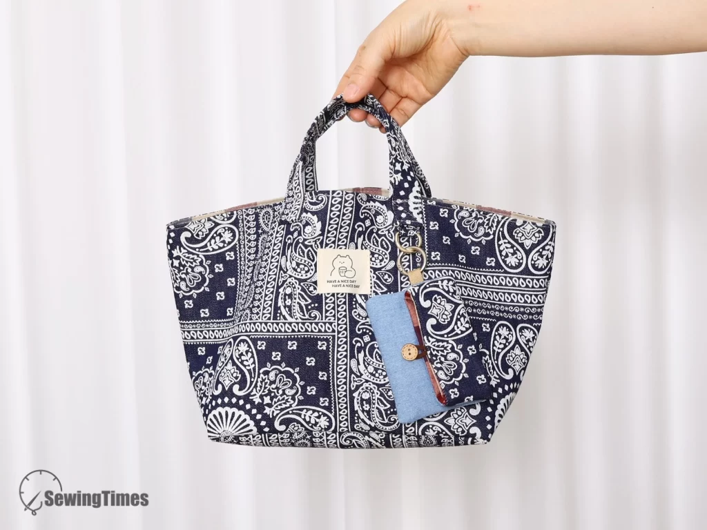 A complete handmade matching set featuring a patterned fabric tote bag and a small pouch, both held stylishly in a woman's hands to show their scale and design.