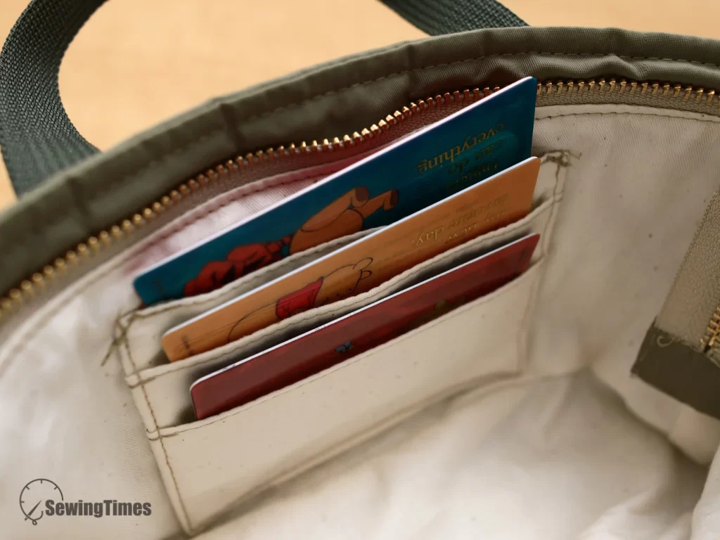 Interior view of the zipper tote bag revealing a clever built-in 3-slot card holder with cards securely tucked inside the lining.