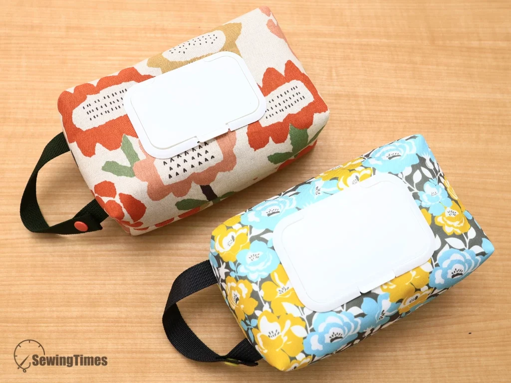 Two handmade fabric wipes cases in orange and blue floral patterns placed together.